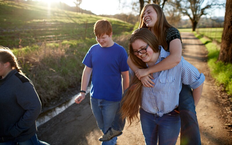 Group of friends walk down dirtroad path, symbolic of their "road to resilience"