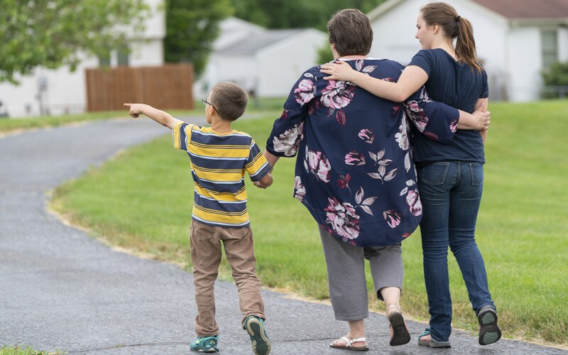 Grandmother and grandchildren walk down path.