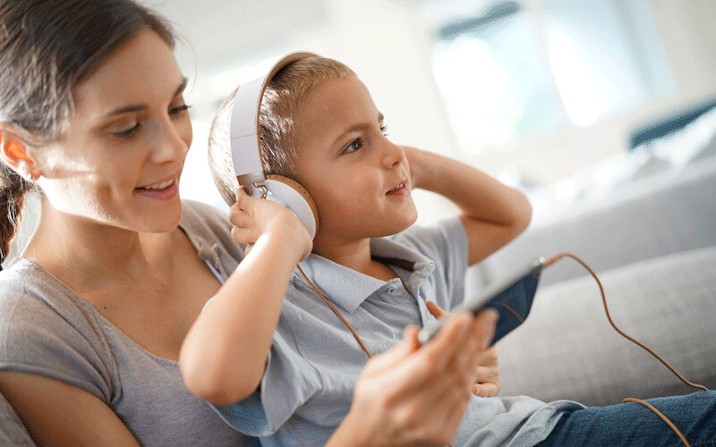 Mom and son using headphones, listening to dad read a story.