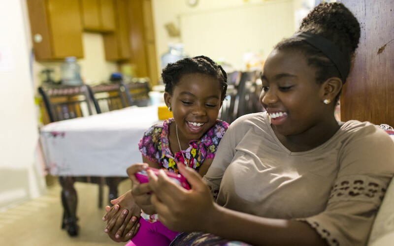 two girls do family history on their phone.