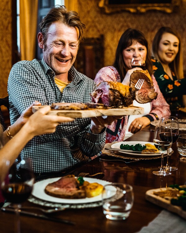 Man passing food to his family at a table.