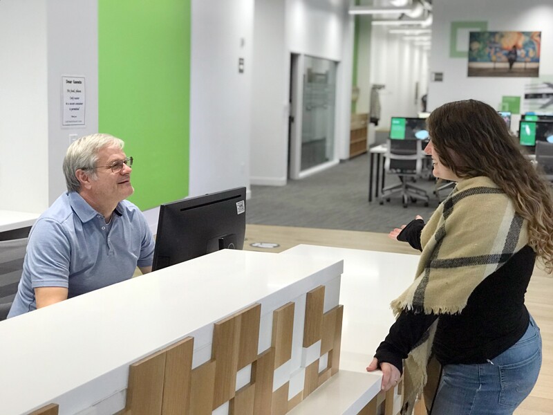 A woman asks a man at a desk for help