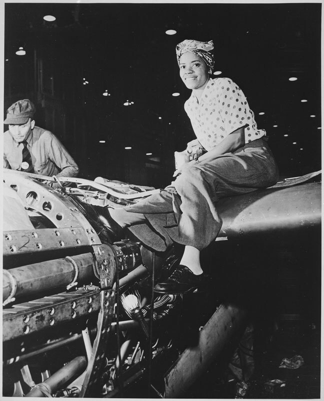 woman working in factory, donning 1940s hair accessories