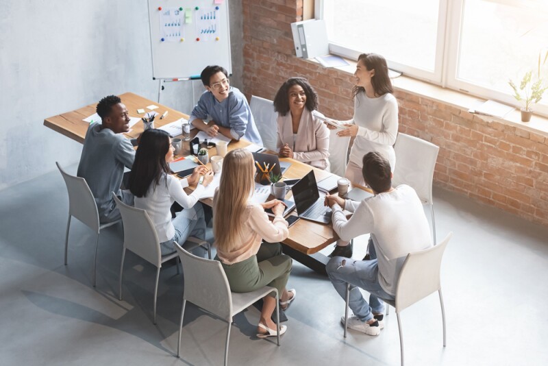 millennials working as a team at work, sitting at table together