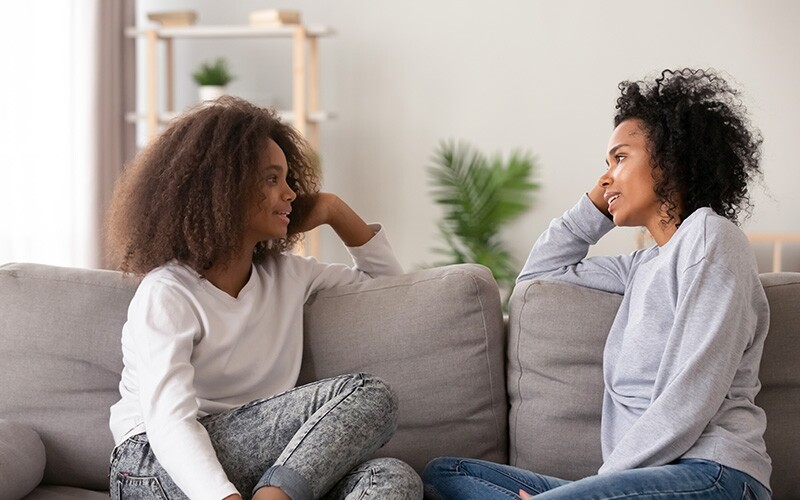 Two women talking and actively listening on couch.