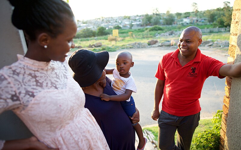 a family speaks together in the doorway of a home.