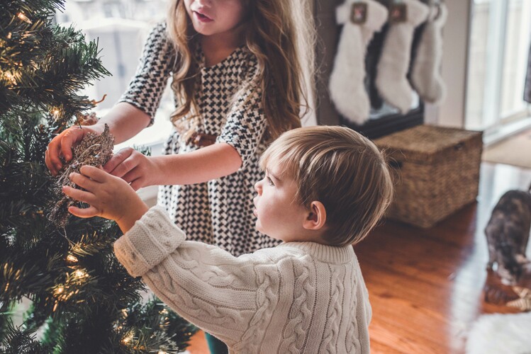 Two children decorate a christmas tree