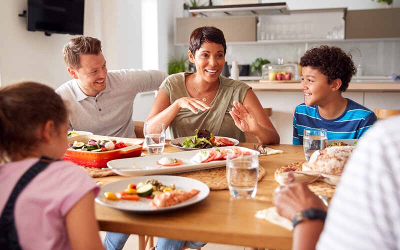 Family plays thanksgiving activity, sits around the table smiling
