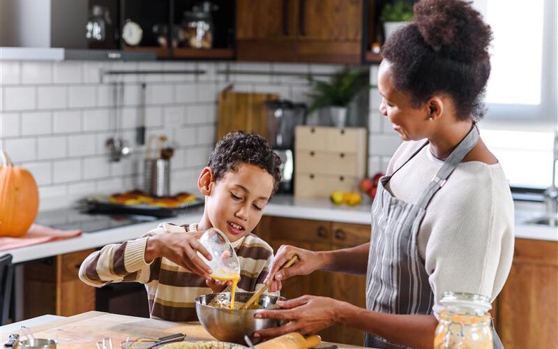 Mother and son make thanksgiving pie together while sharing family stories.