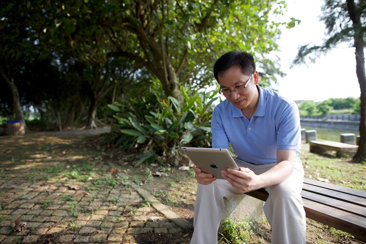 a man journals from a bench on his digital journaling device.