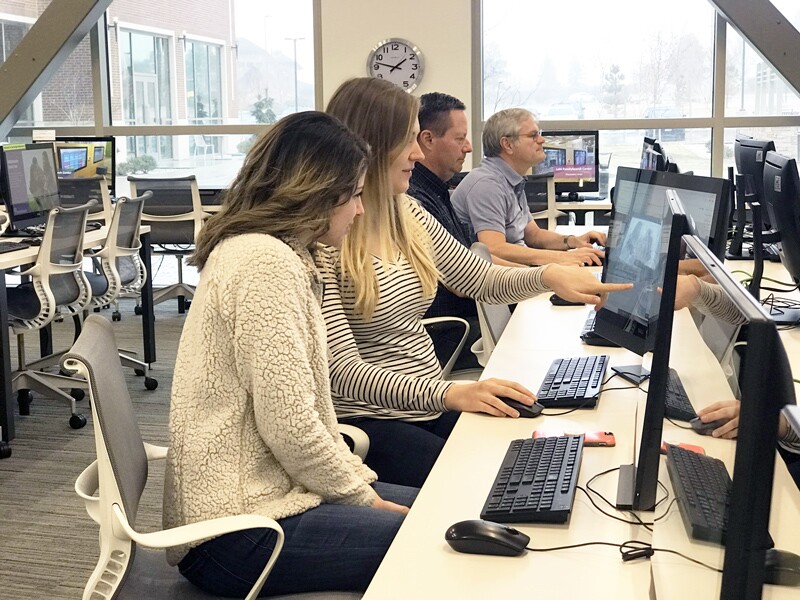 Two girls help each other on computers