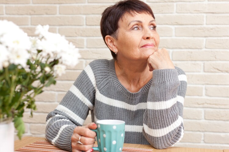 generation x woman holding a cup looking away