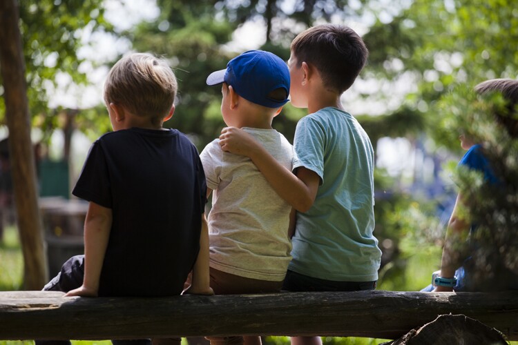 Three children sit with their arms around each other. 