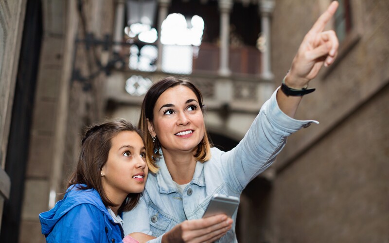 An older woman and a young girl point out a building on a heritage tour