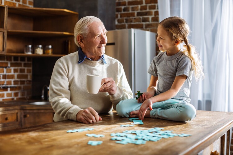 a grandpa and granddaughter do a puzzle together.