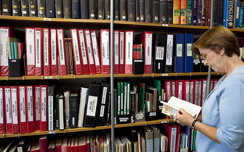 A woman reads a reference book in a library.