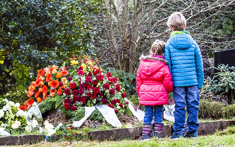 Boy and girl standing at memorial of their loved one.