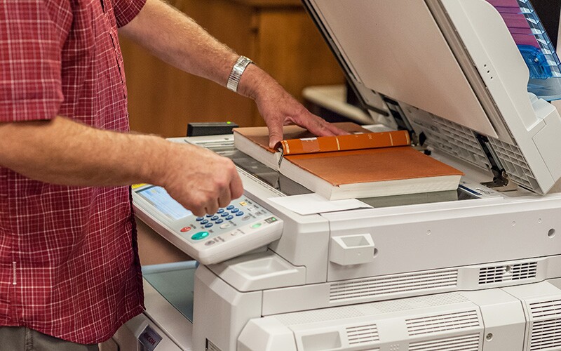 Man copying a book on a photocopy machine.