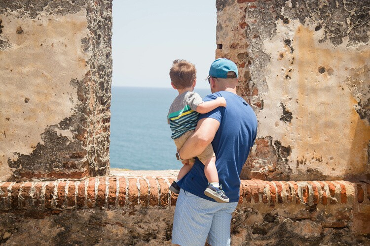 a puerto rican father and son look out onto the ocean.