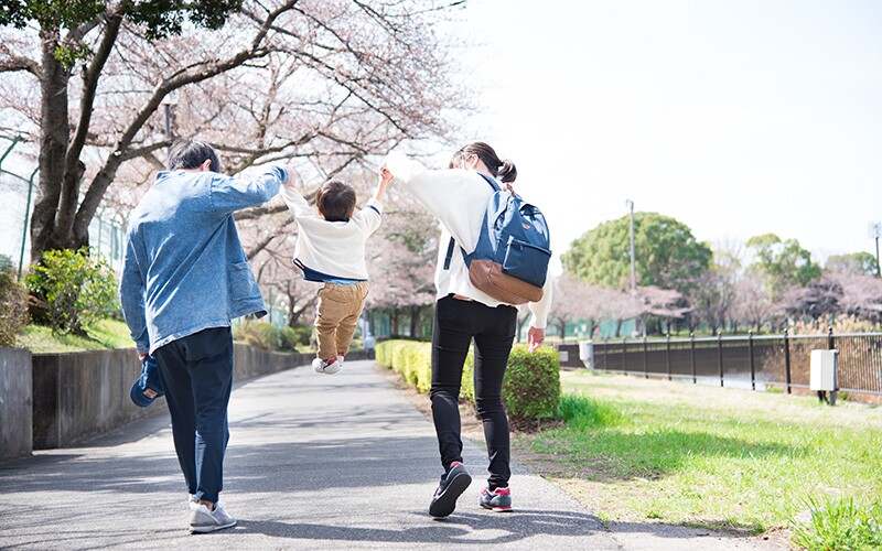 a japanese mother and father swing their son. 