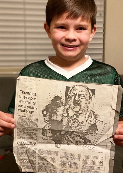 Charlie Flood's descendant holding an original copy of the newspaper article he wrote.