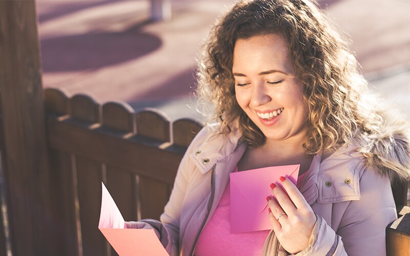 A woman smiles while reading a friendship card.