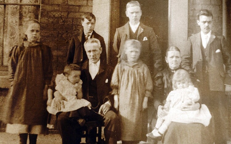 A family with their children (boys and girls) standing around them.