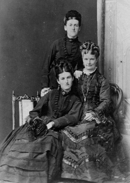 Three women wearing 1870s fashion trends.