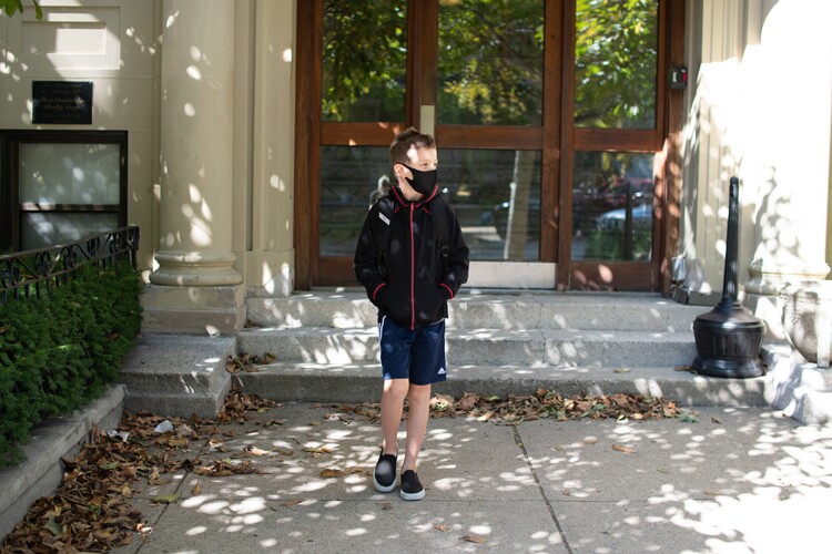 a boy goes to school wearing a face mask.