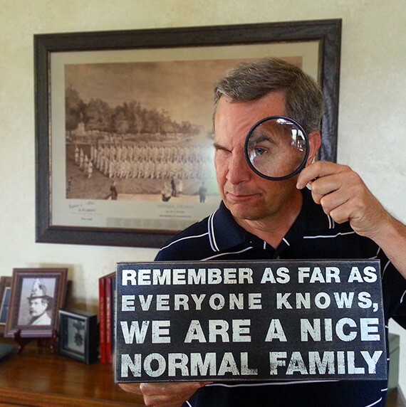 Scott Fisher holding sign that says "Remember as far as anyone knows, we are a nice normal family."