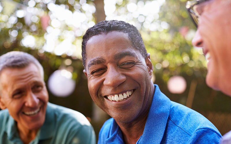 A group of male friends smile and laugh together.