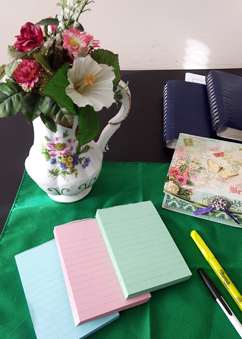 Paper and pens laid out on a table with flowers at a funeral.